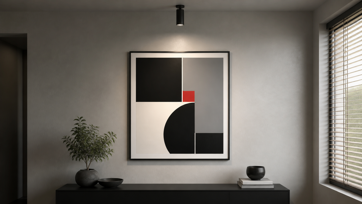 Black white and red abstract wall art lit by a directional spotlight beside shaded windows