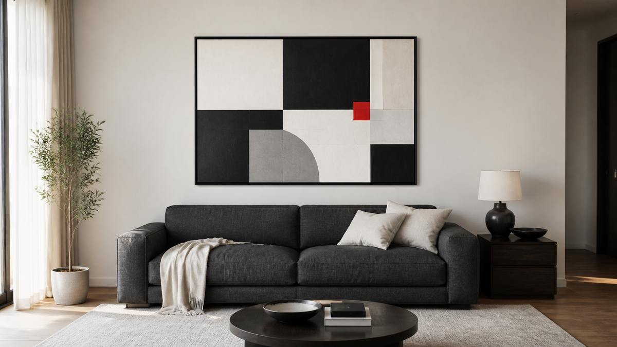 Large black white and red abstract artwork positioned above a charcoal sofa